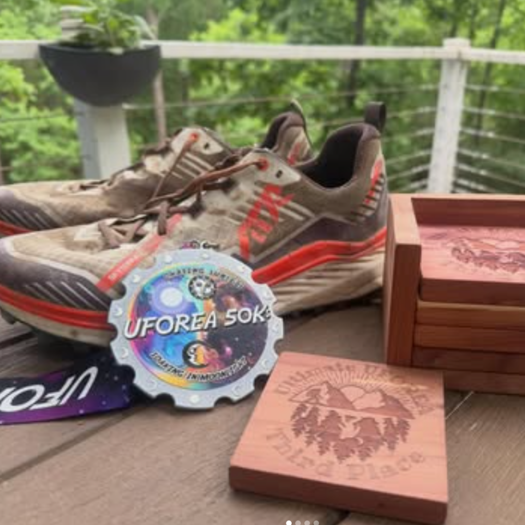 Pair of running shoes with a 'UFOREA 50KS' logo on a wooden surface outdoors.