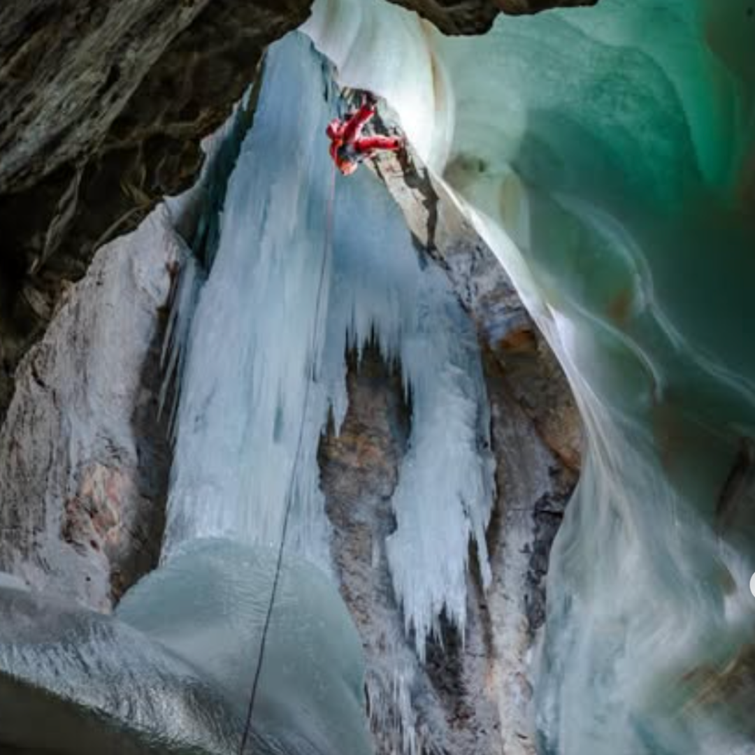 Person ice climbing on a frozen waterfall inside a cave