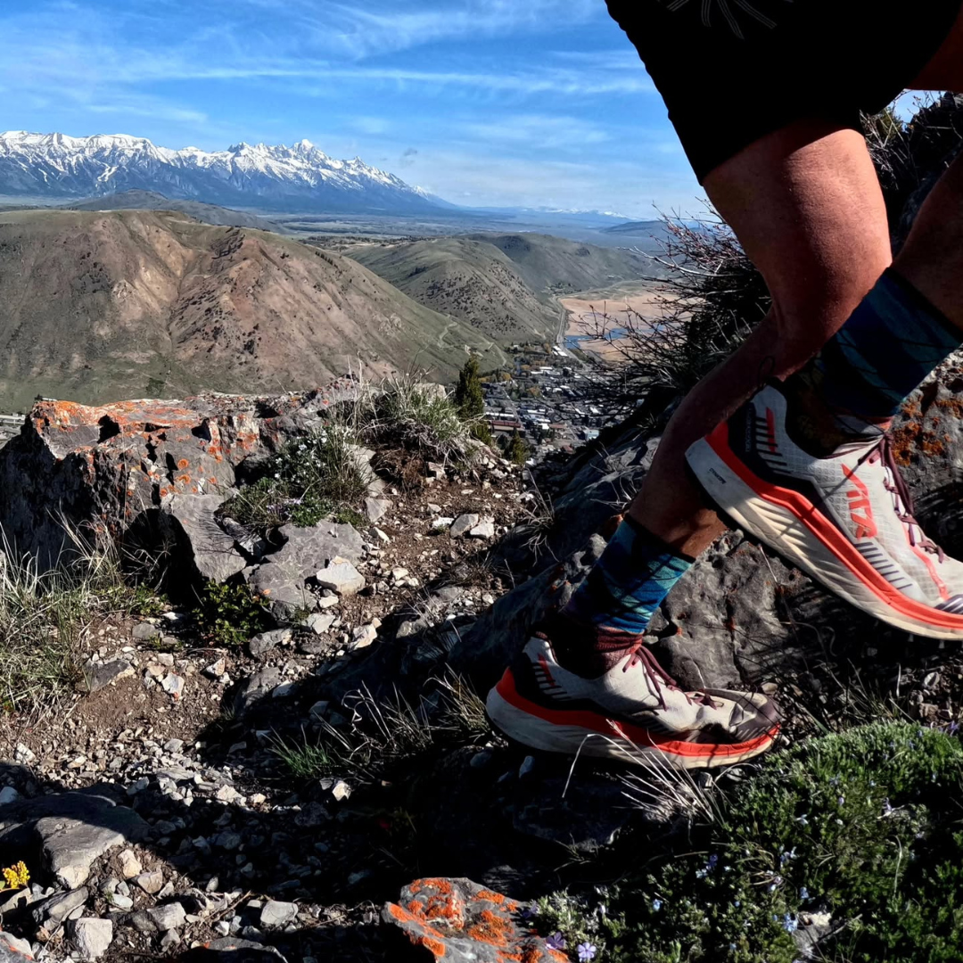 A close up of orange and white LOWA Skyterra running shoes on a mountain landscape